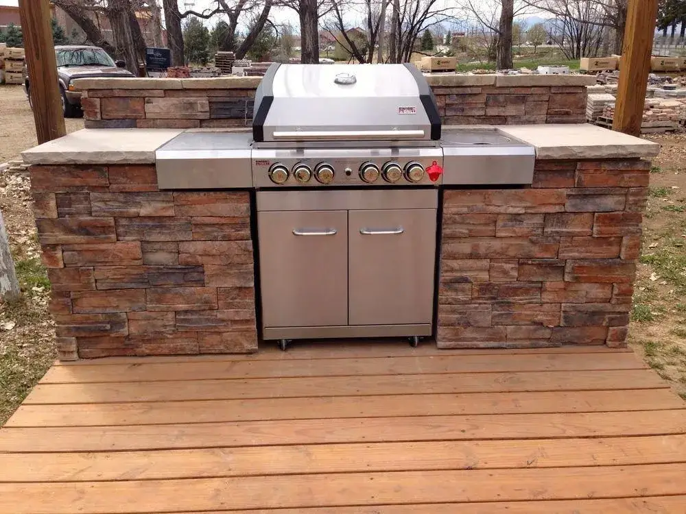 A person comfortably using a well-designed grill with spacious side shelves.